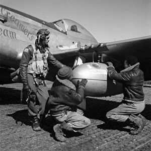 WWII: TUSKEGEE AIRMEN, 1945. Edward Gleed and two other Tuskegee Airmen adjust an external 75 gallon drop tank on the wing of a P-5 / D fighter plane Creamers Dream, at Ramitelli Airfield, Italy. Photograph by Toni Frissell, March 1945