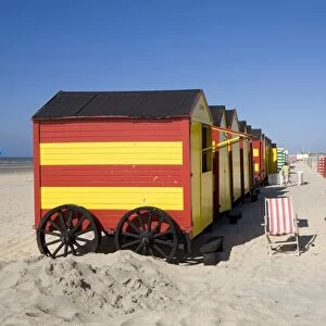 Belgium, De Panne, row of old fashioned striped beach huts, and deckchairs