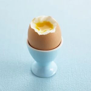 Boiled egg in blue egg cup showing yolk