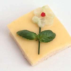 Cheese open sandwich garnished with a flower decoration made from herbs and cucumber