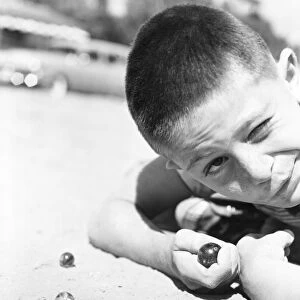 Close-up of young boy playing marbles in the dirt