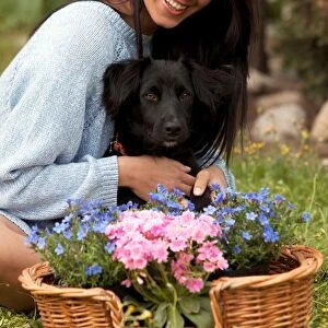 Girl with a Basket of Flowers While Embracing a Dog