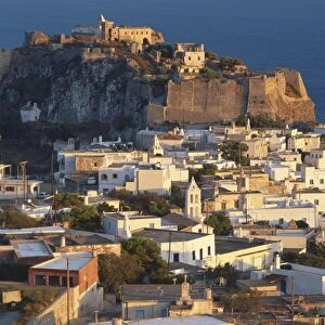 Greece, Kythira, Chora at dusk, houses clustered on hillside, ruins on clifftop