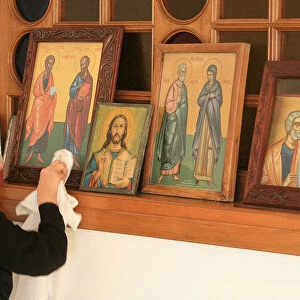 Greek orthodox woman cleaning icons