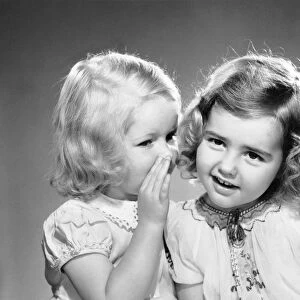 Two little girls telling secrets