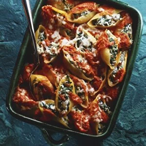 Pasta shells stuffed with spinach and cheese and topped with tomato sauce, in a baking dish, view from above