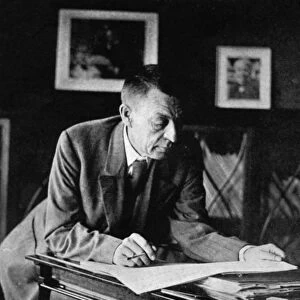 Russian composer, sergei v, rachmaninov, looking over a manuscript at his piano in the late 1920s