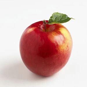 Shiny red apple with green leaf attached to stem