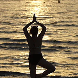 Woman having yoga meditation on beach at sunset. Silence and relaxation concept