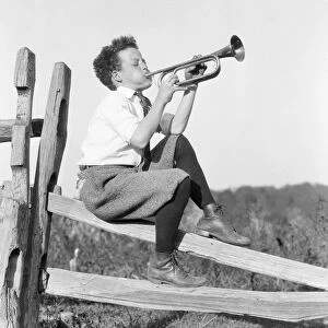 Boy sitting on fence, playing musical instrument