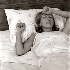 Close-Up Woman Lying In Bed With Pained Expression Holding Hand To Forehead Indoor