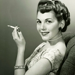 Elegant woman smoking cigarette, posing in studio, (B&W), portrait