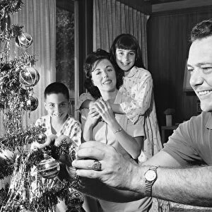 Family in living room, father decorating Christmas tree