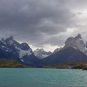 Looking across the cold waters of Lake Pehue to the snow-capped mountain peaks of the Torres del Paine National Park in the Magallanes Region of Patagonia, Southern Chile