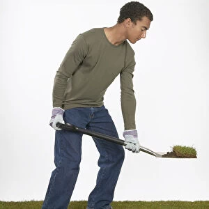 Man holding a spade with section of turf on the blade