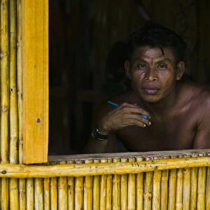 Man looking out window of bamboo hut, portrait