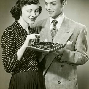 Man offering woman box of chocolates