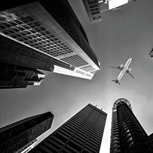Tall city buildings and a plane flying overhead