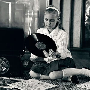 Teen girl with vinyl records and record player, sitting on floor