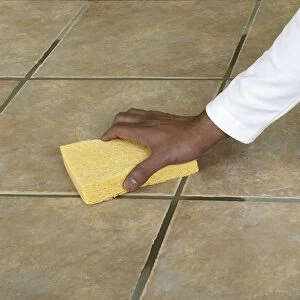 Wiping the surface of a tiled floor with a sponge