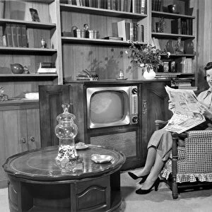 Woman relaxing at home with newspaper
