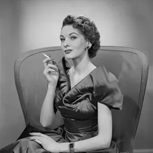 Woman smoking cigarette in armchair, portrait
