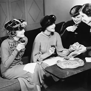Four women drinking wine, talking in living room (B&W)