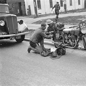 An army motorcyclist performs some maintenance on his Royal Enfield 25 CC motorcycles