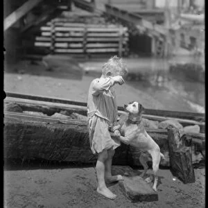 Barefoot boy, possibly William Gray Hassler, plays with dog on the shore of a river or