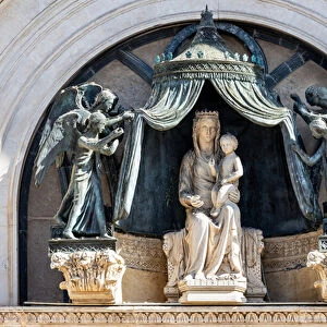 The facade, the central lunette: copy of the Madonna with Child and six angels holding a curtain (marble, bronze, polychrome, gold and glass paste)