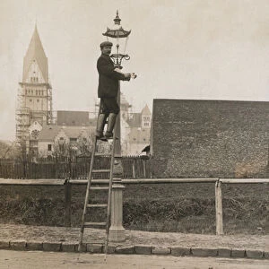 Man up a ladder fixing a street lamp (b / w photo)
