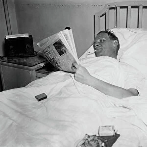 Man Smoking Cigarette while Reading Newspaper in Hospital Bed, 1936 (b/w photo)