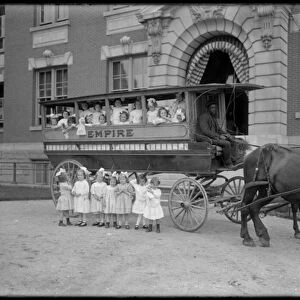 Small girls pose in and in front of a horse-drawn wagon