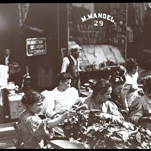 View of women shopping for vegetables from a peddler on Hester Street, New York