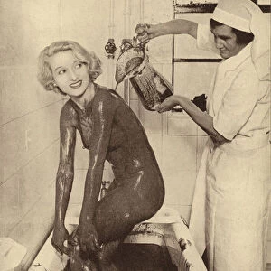 Woman having a mud bath treatment at a beauty salon (b / w photo)