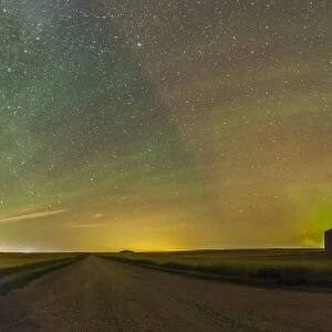 Aurora borealis behind grain bins on a country road in Alberta, Canada