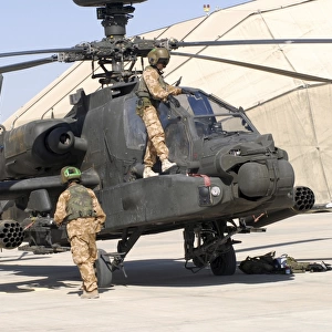 British soldiers perform maintenance on an Apache helicopter