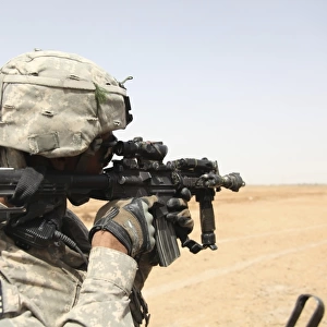 U. S. Army soldier scans the horizon through the scope of a M4 carbine