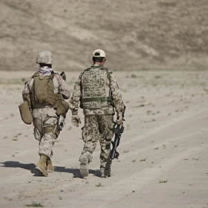 U. S. Marine and German soldier walk in a wadi near Kunduz, Afghanistan