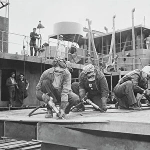 Three women chippers working in a shipbuilding shipyard