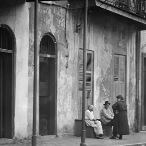 View from across street of people talking, New Orleans, between 1920 and 1926. Creator: Arnold Genthe