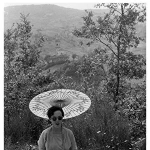 Woman under a parasol having a picnic, c1950-1969(?)