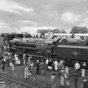 People viewing steam train Evening Star by engine shed; England