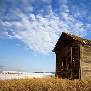 A Wooden Shed Stands Alone In A Snow Covered Field; Alberta, Canada