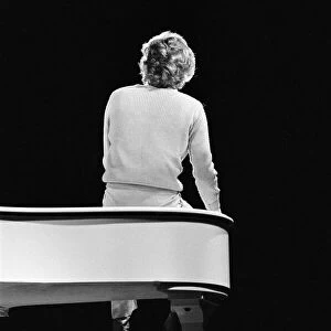 Barry Manilow, pictured from behind sitting on a piano, during rehearsals for his
