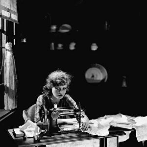 Corinne Griffith seen here in the role of Mary Boyne sitting working at a Singer sewing
