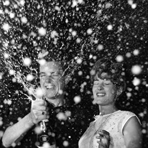 Couple celebrate the new year with a bottle of champagne 1st January 1965