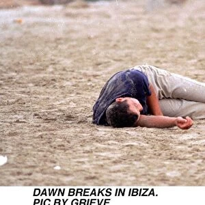 Dawn breaks in Ibiza Spain Drink Drunk youth Young man sleeps it off on the beach