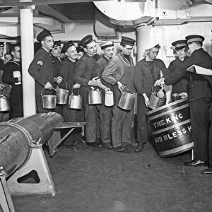 Below deck of HMS George V, a line of seamen queue to collect the daily rum ration for
