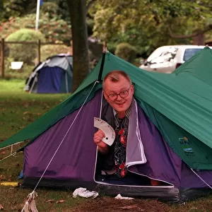 Edinburgh Festival August 1999 Man poking head out of tent holding palying cards